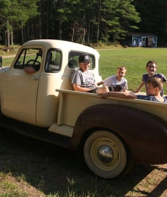 “Campers working together on a vintage truck at the Long Lake automotive activity