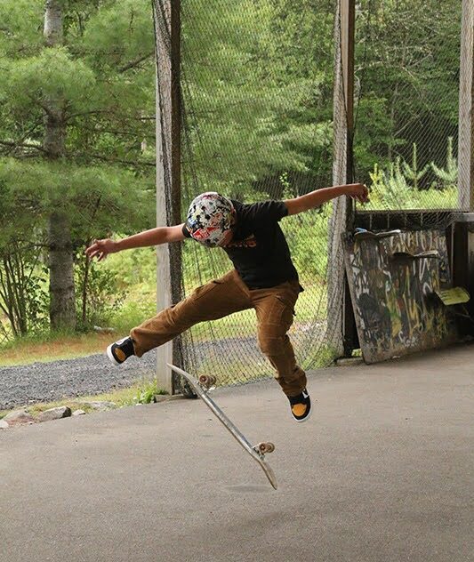 amper performing a scooter trick on the outdoor ramp at Long Lake Camp Adventures