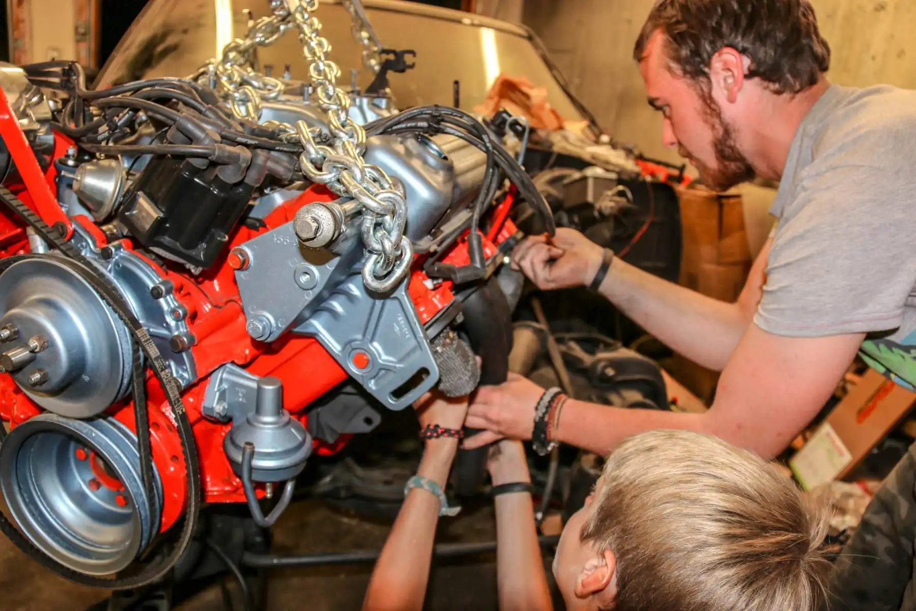 Campers learning engine repair on a car at summer camp.