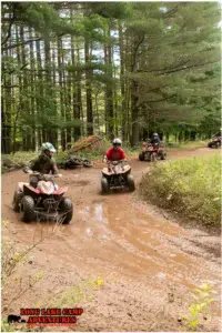 Campers riding ATVs through a muddy trail at Long Lake Camp Adventures.