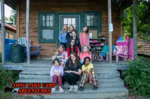 Campers and counselors sitting outside overnight cabins at Long Lake Camp Adventures in New York