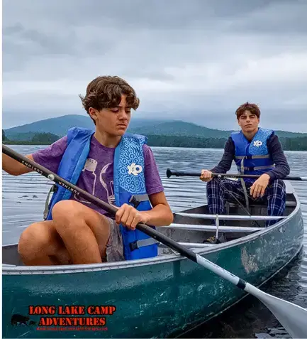 Two campers canoeing on the lake at Long Lake Camp Adventures during fishing summer camp.